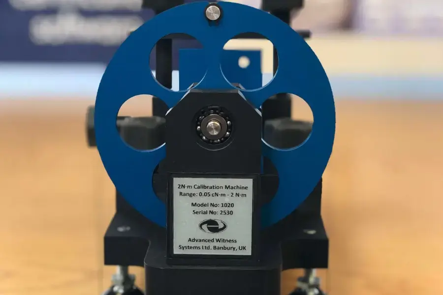 A torque calibration wheel on a wooden benchtop calibration rig