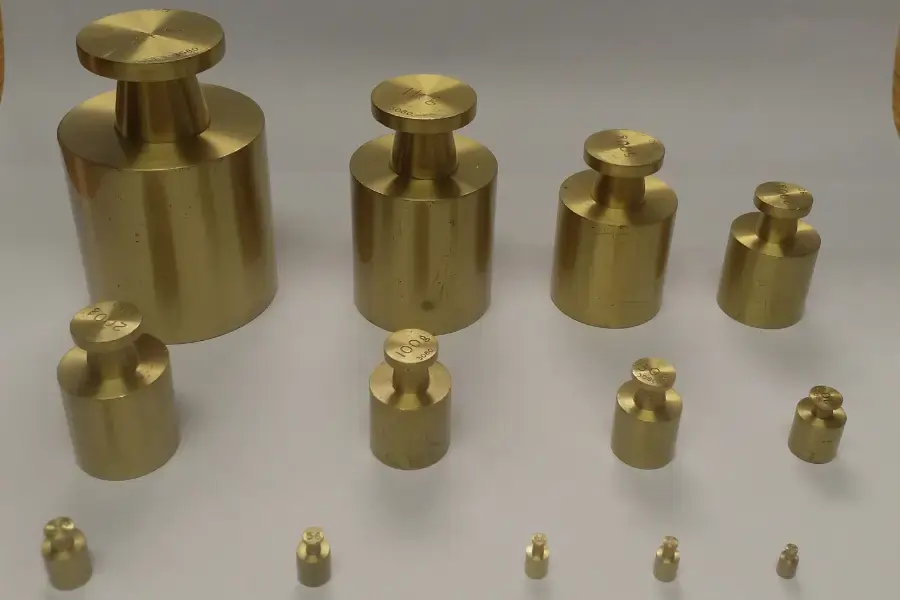 Set of 15 brass weights on a white sheet of paper