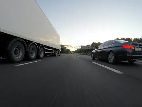 A white lorry and a black car side by side on a motorway