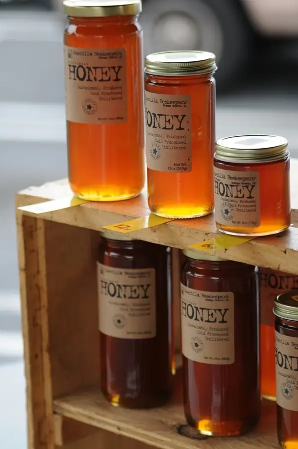 Jars of honey on a makeshift wooden stand outside