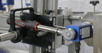 A torque wrench being calibrated in an automated calibrator